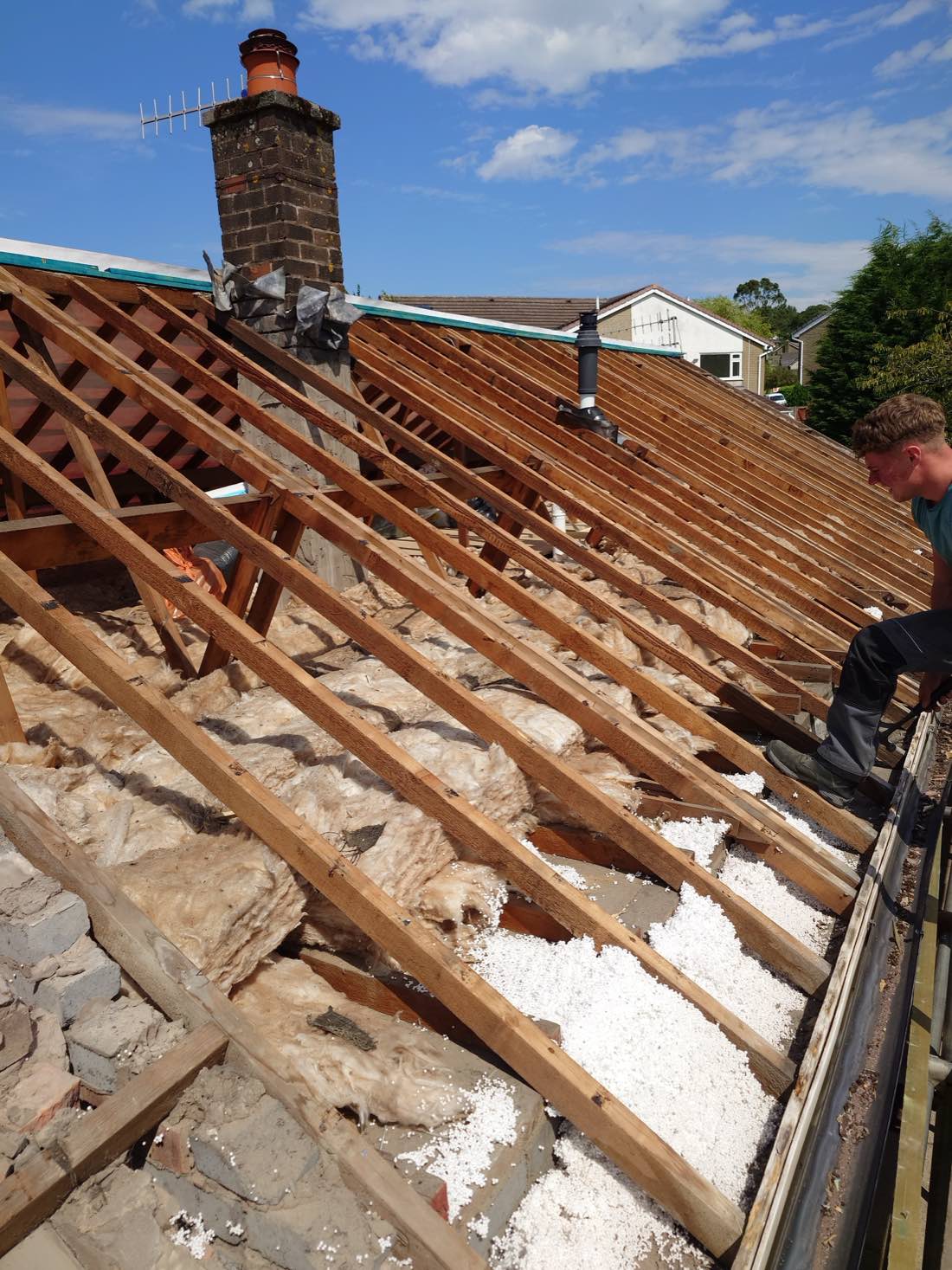 A roof stripped back to the rafters, the chimney stack still standing